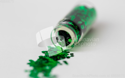 Image of green glitters poured from small glass bottle