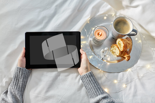 Image of hands with tablet pc, croissant and coffee in bed