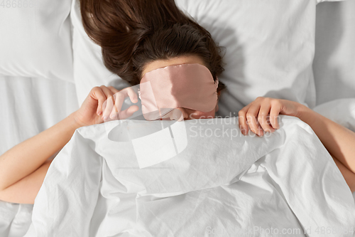 Image of woman with eye sleeping mask in bed under blanket