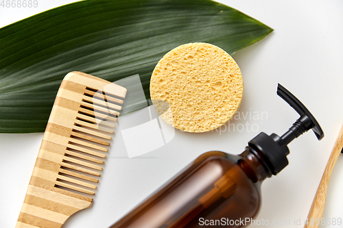 Image of comb, sponge, liquid soap or shower gel and leaf