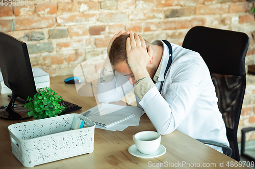 Image of Caucasian doctor resting after consulting for patient, working in cabinet