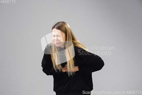 Image of Young woman suffers from pain, feels sick, ill and weakness isolted on studio background