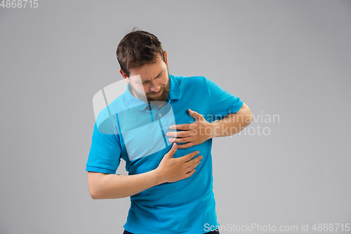 Image of Young man suffers from pain, feels sick, ill and weakness isolted on studio background