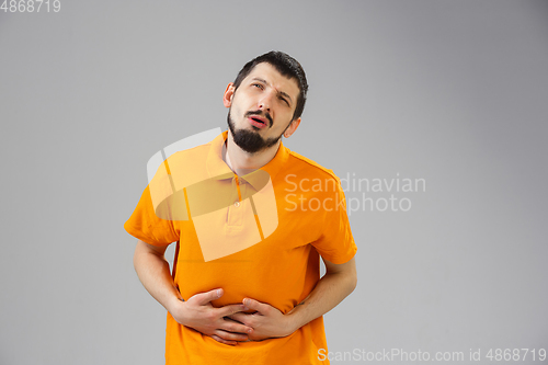 Image of Young man suffers from pain, feels sick, ill and weakness isolted on studio background