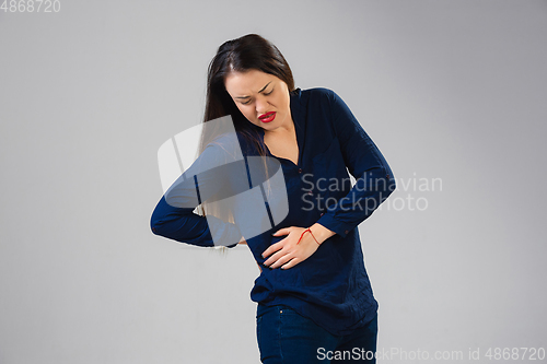 Image of Young woman suffers from pain, feels sick, ill and weakness isolted on studio background