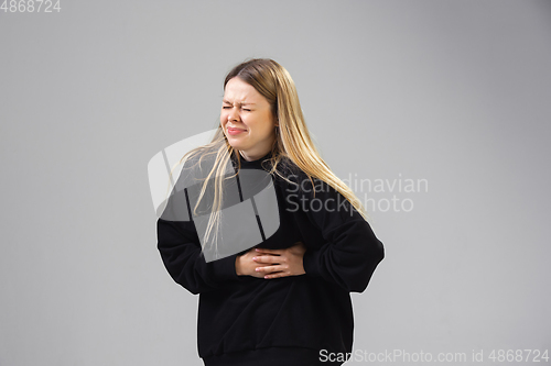 Image of Young woman suffers from pain, feels sick, ill and weakness isolted on studio background