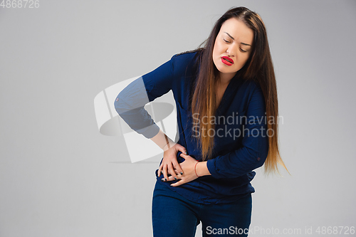 Image of Young woman suffers from pain, feels sick, ill and weakness isolted on studio background