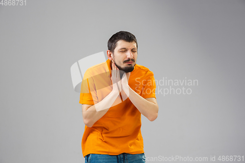 Image of Young man suffers from pain, feels sick, ill and weakness isolted on studio background