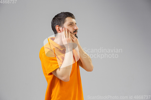 Image of Young man suffers from pain, feels sick, ill and weakness isolted on studio background