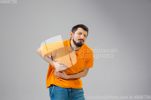 Image of Young man suffers from pain, feels sick, ill and weakness isolted on studio background