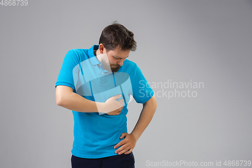 Image of Young man suffers from pain, feels sick, ill and weakness isolted on studio background