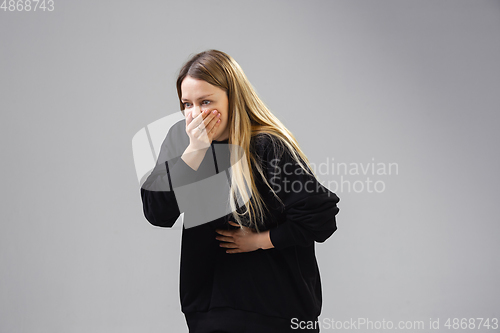 Image of Young woman suffers from nausea, feels sick, ill and weakness isolted on studio background