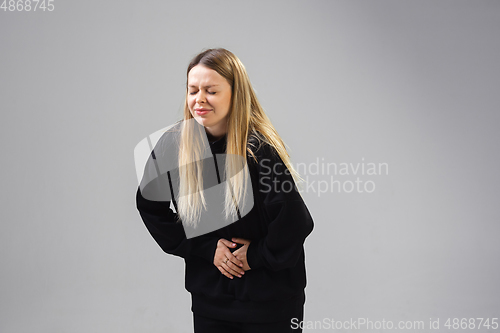 Image of Young woman suffers from pain, feels sick, ill and weakness isolted on studio background