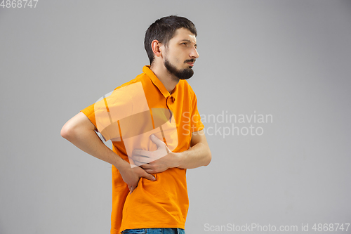 Image of Young man suffers from pain, feels sick, ill and weakness isolted on studio background