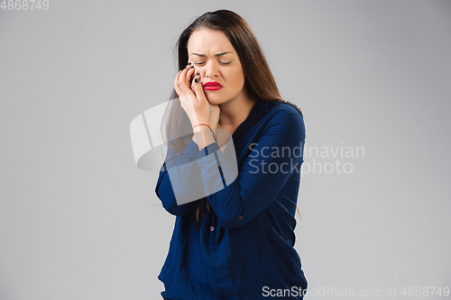 Image of Young woman suffers from pain, feels sick, ill and weakness isolted on studio background