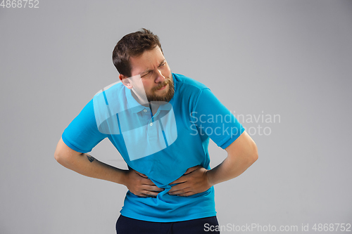 Image of Young man suffers from pain, feels sick, ill and weakness isolted on studio background