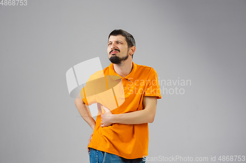 Image of Young man suffers from pain, feels sick, ill and weakness isolted on studio background