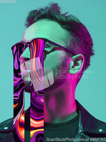 Image of Modern man\'s portrait on studio background in bright neon light, stylish creative design