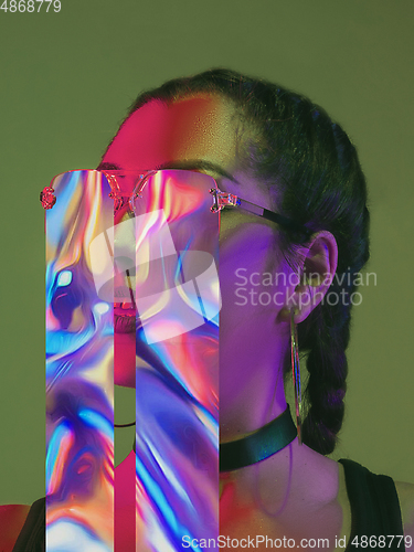Image of Modern woman\'s portrait on studio background in bright neon light, stylish creative design