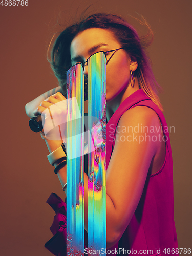 Image of Modern woman\'s portrait on studio background in bright neon light, stylish creative design