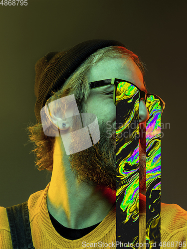 Image of Modern man\'s portrait on studio background in bright neon light, stylish creative design
