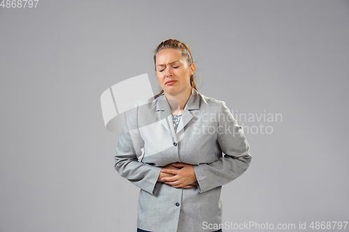 Image of Young woman suffers from pain, feels sick, ill and weakness isolted on studio background