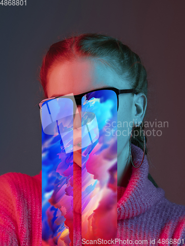 Image of Modern woman\'s portrait on studio background in bright neon light, stylish creative design