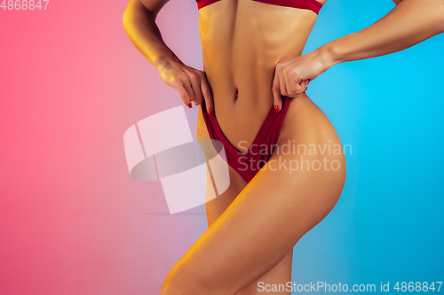 Image of Close up of young fit and sportive woman in stylish red swimwear on gradient background. Perfect body ready for summertime.