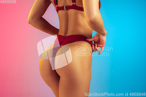Image of Close up of young fit and sportive woman in stylish red swimwear on gradient background. Perfect body ready for summertime.