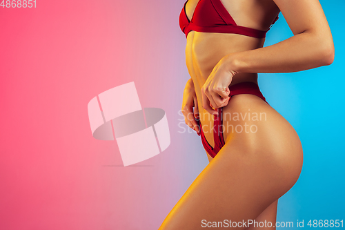 Image of Close up of young fit and sportive woman in stylish red swimwear on gradient background. Perfect body ready for summertime.