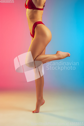 Image of Close up of young fit and sportive woman in stylish red swimwear on gradient background. Perfect body ready for summertime.