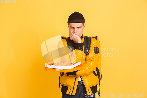 Image of Contacless delivery service during quarantine. Man delivers food and shopping bags during insulation. Emotions of deliveryman isolated on yellow background.