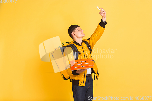 Image of Contacless delivery service during quarantine. Man delivers food and shopping bags during insulation. Emotions of deliveryman isolated on yellow background.