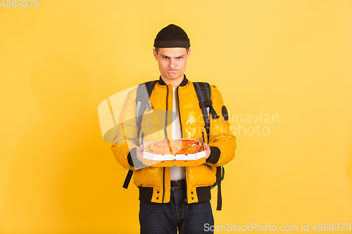 Image of Contacless delivery service during quarantine. Man delivers food and shopping bags during insulation. Emotions of deliveryman isolated on yellow background.