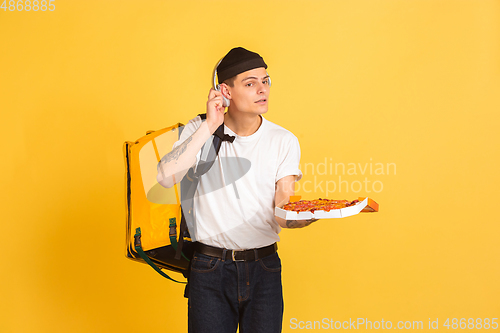 Image of Contacless delivery service during quarantine. Man delivers food and shopping bags during insulation. Emotions of deliveryman isolated on yellow background.