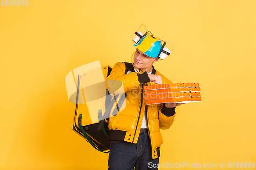 Image of Contacless delivery service during quarantine. Man delivers food and shopping bags during insulation. Emotions of deliveryman isolated on yellow background.