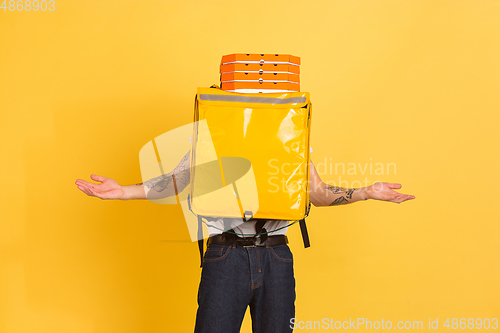 Image of Contacless delivery service during quarantine. Man delivers food and shopping bags during insulation. Emotions of deliveryman isolated on yellow background.