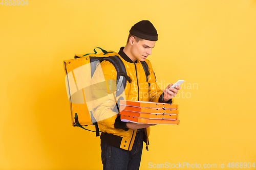 Image of Contacless delivery service during quarantine. Man delivers food and shopping bags during insulation. Emotions of deliveryman isolated on yellow background.