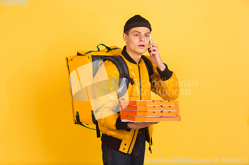 Image of Contacless delivery service during quarantine. Man delivers food and shopping bags during insulation. Emotions of deliveryman isolated on yellow background.