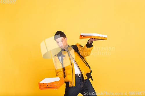 Image of Contacless delivery service during quarantine. Man delivers food and shopping bags during insulation. Emotions of deliveryman isolated on yellow background.