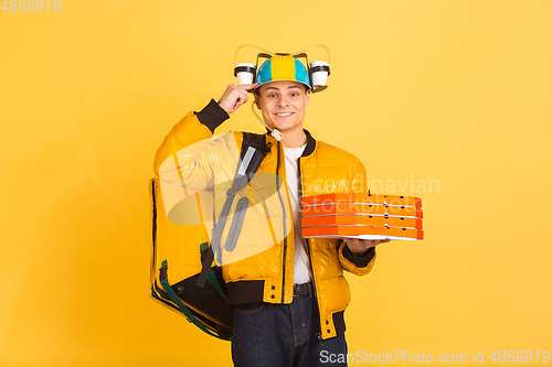 Image of Contacless delivery service during quarantine. Man delivers food and shopping bags during insulation. Emotions of deliveryman isolated on yellow background.