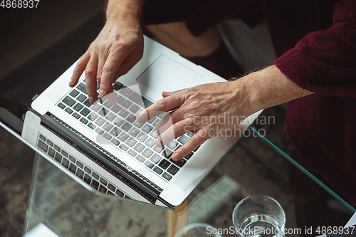 Image of Mature senior older man during quarantine, realizing how important stay at home during virus outbreak, close up of hands typing text