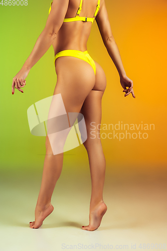 Image of Close up of young fit and sportive woman in stylish yellow swimwear on gradient background. Perfect body ready for summertime.