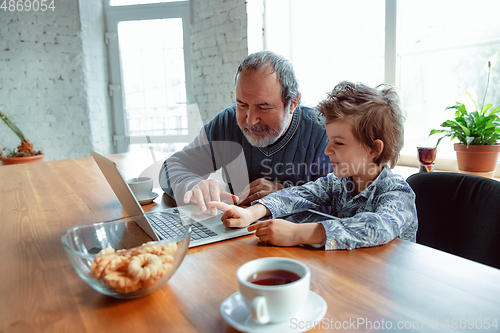 Image of Grandfather and his grandson spending time insulated at home, stadying, watching cinema, shopping together