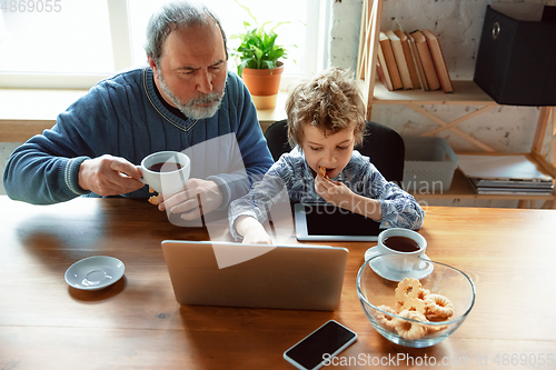 Image of Grandfather and his grandson spending time insulated at home, stadying, watching cinema, shopping together