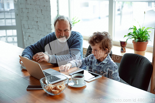 Image of Grandfather and his grandson spending time insulated at home, stadying, watching cinema, shopping together