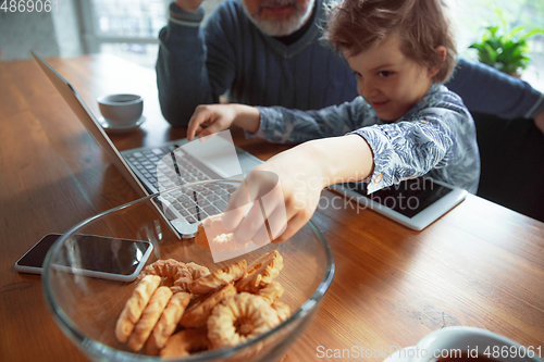 Image of Grandfather and his grandson spending time insulated at home, stadying, watching cinema, shopping together