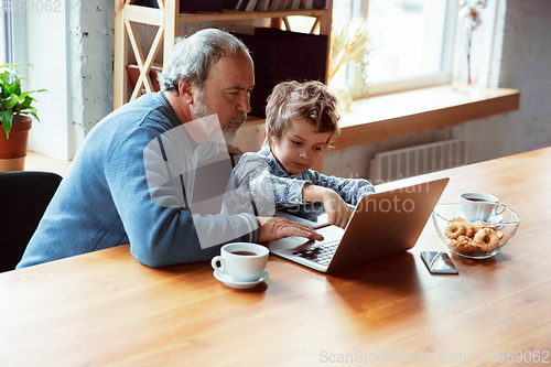 Image of Grandfather and his grandson spending time insulated at home, stadying, watching cinema, shopping together