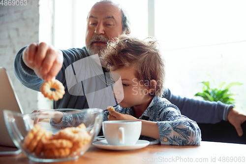 Image of Grandfather and his grandson spending time insulated at home, stadying, watching cinema, shopping together