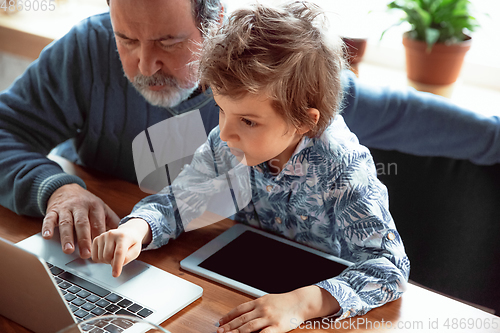 Image of Grandfather and his grandson spending time insulated at home, stadying, watching cinema, shopping together